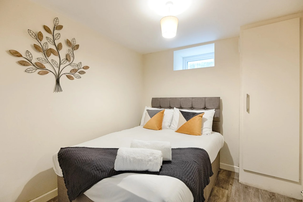 Woodlands House bedroom with decorative leaf wall art and grey headboard