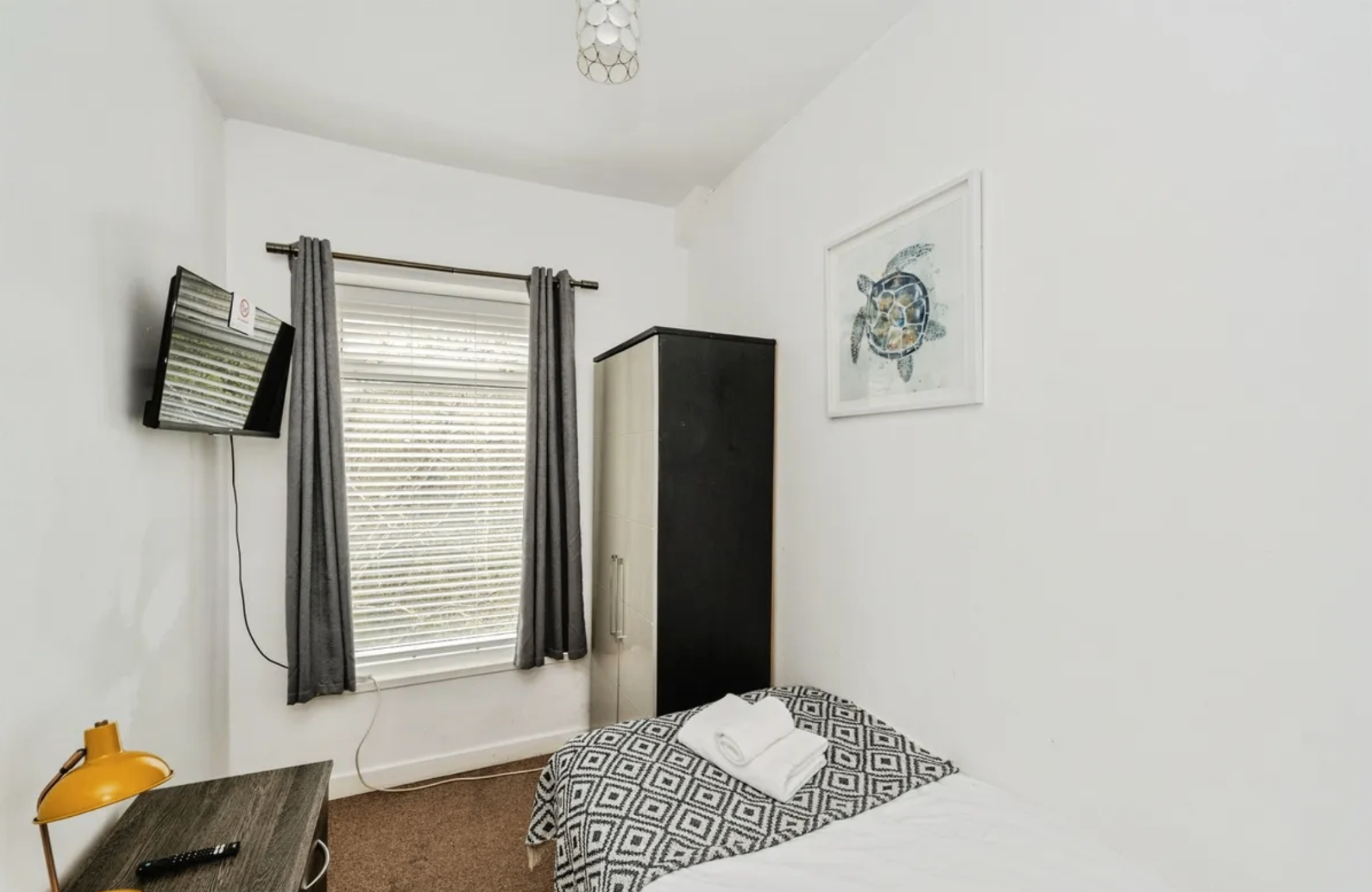Woodlands House bedroom with wall-mounted television and turtle artwork